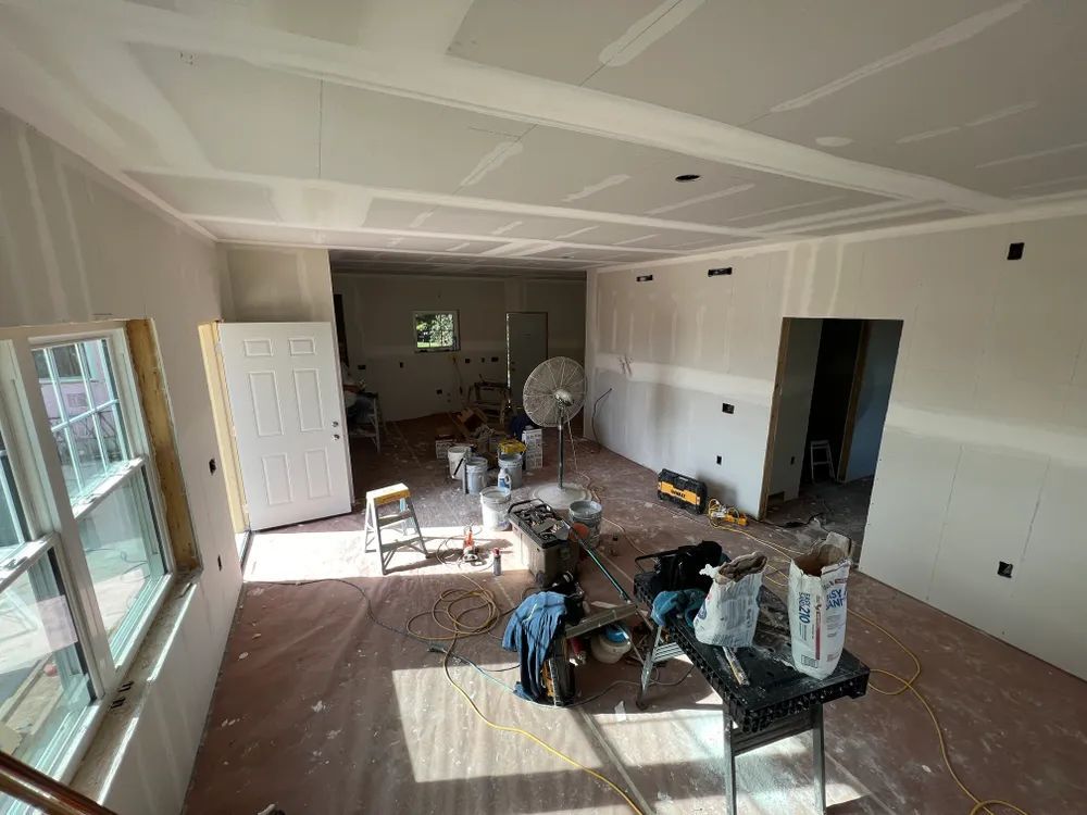 A large room with a table and a fan in it is being remodeled.