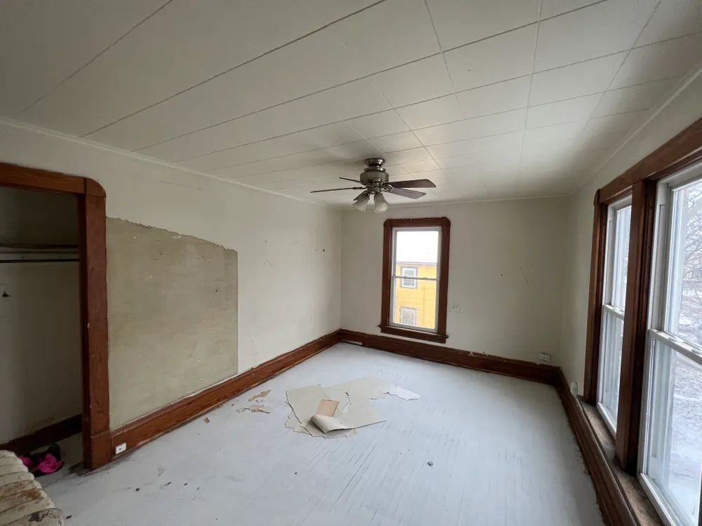 An empty room with a ceiling fan and a lot of windows.