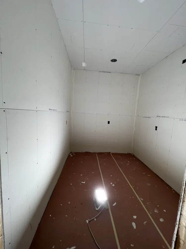 An empty room with white walls and a red floor