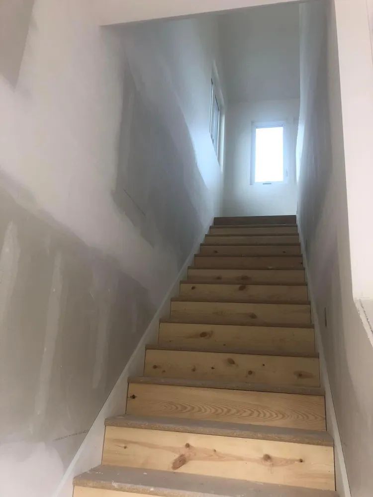 A set of wooden stairs leading up to a window in a house.