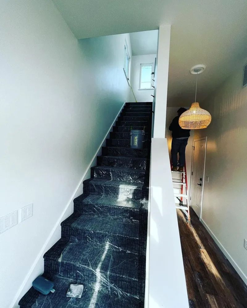 A man is standing on a ladder next to a set of stairs.