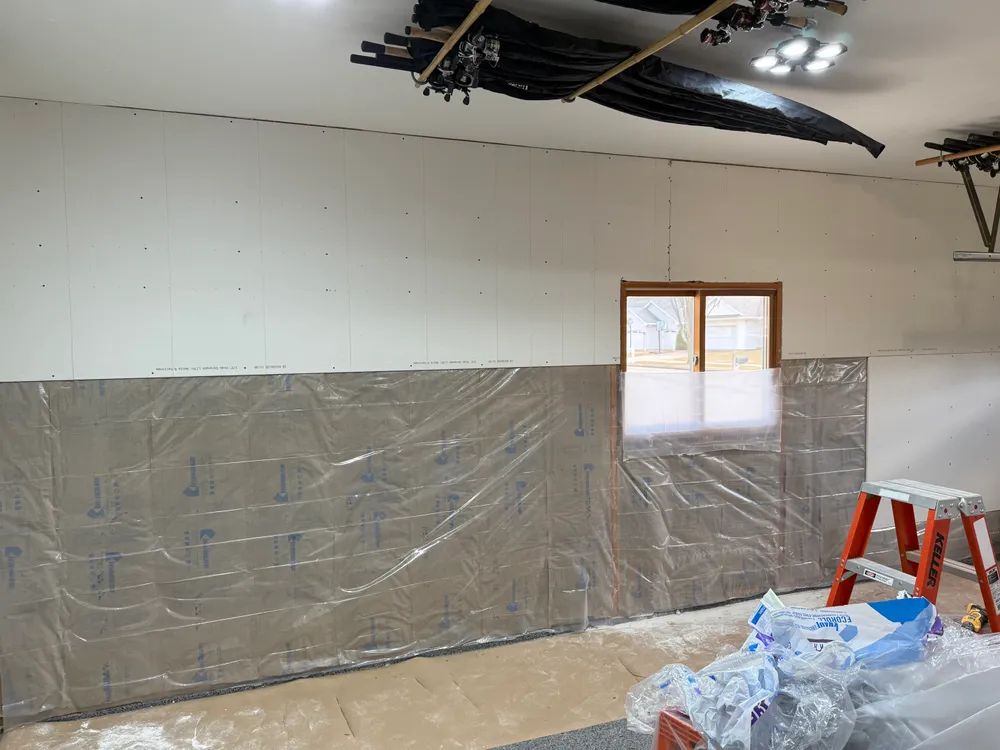 A room with a ladder and a window covered in plastic.