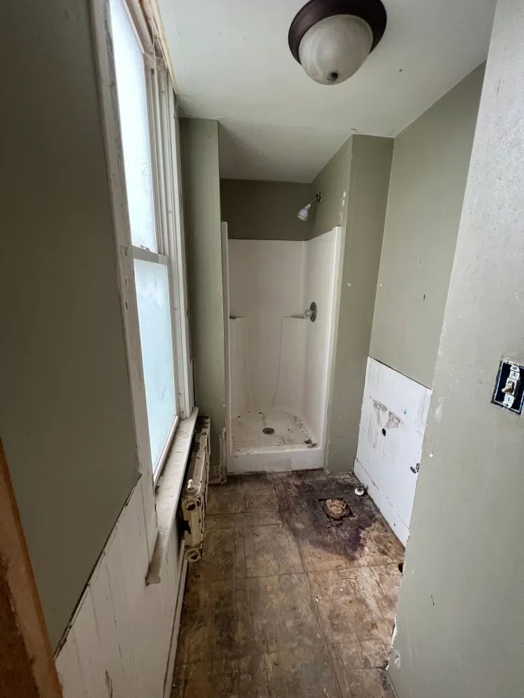 A bathroom with a shower and a window.