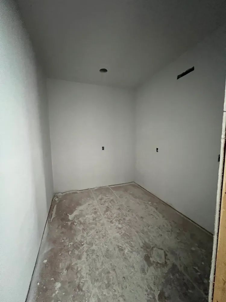 An empty room with white walls and a concrete floor.
