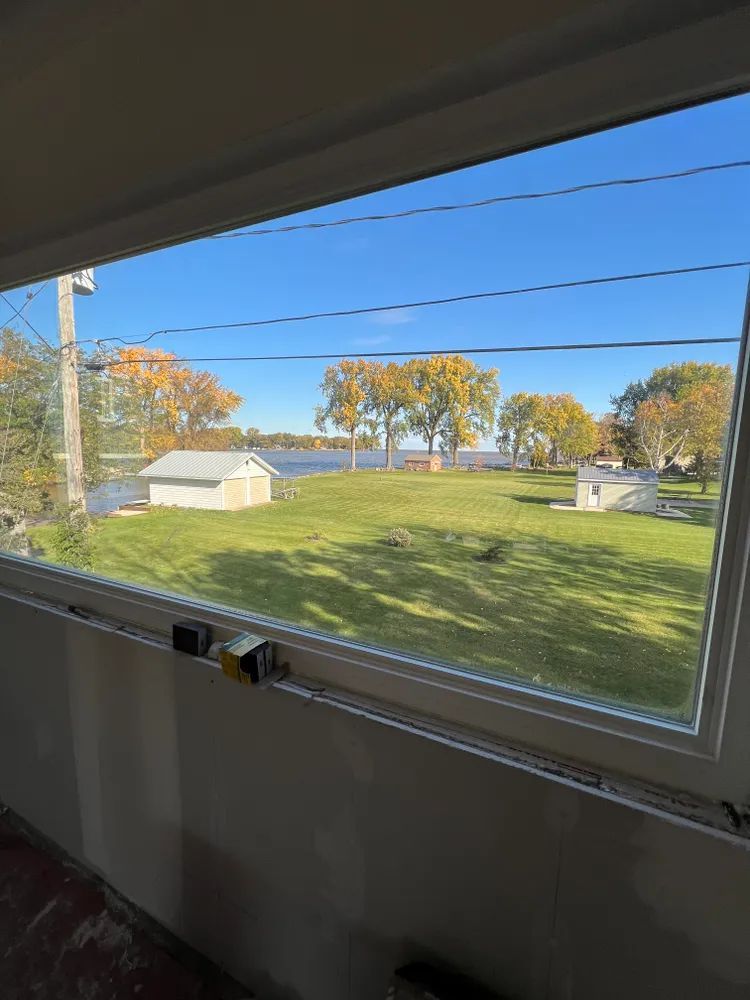 A large window with a view of a field and a lake.