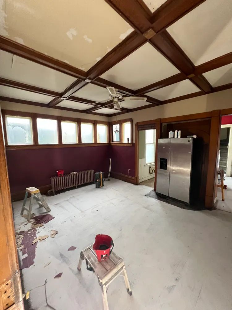 A room with a refrigerator and a ladder in it.