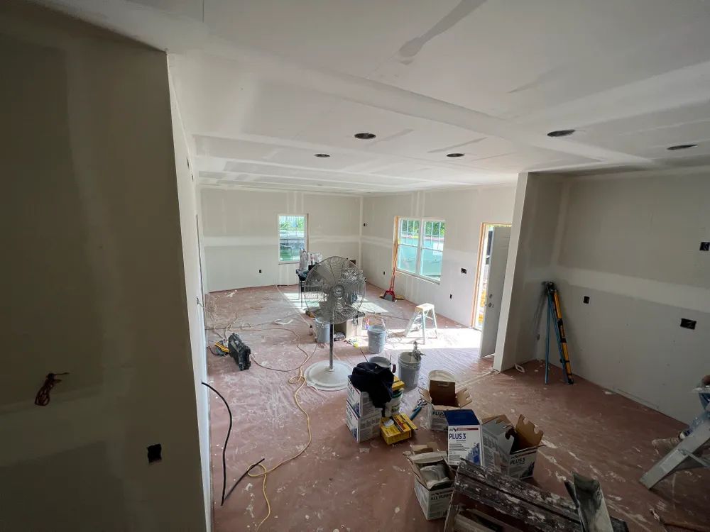 A large room with a ladder in the middle of it is being remodeled.