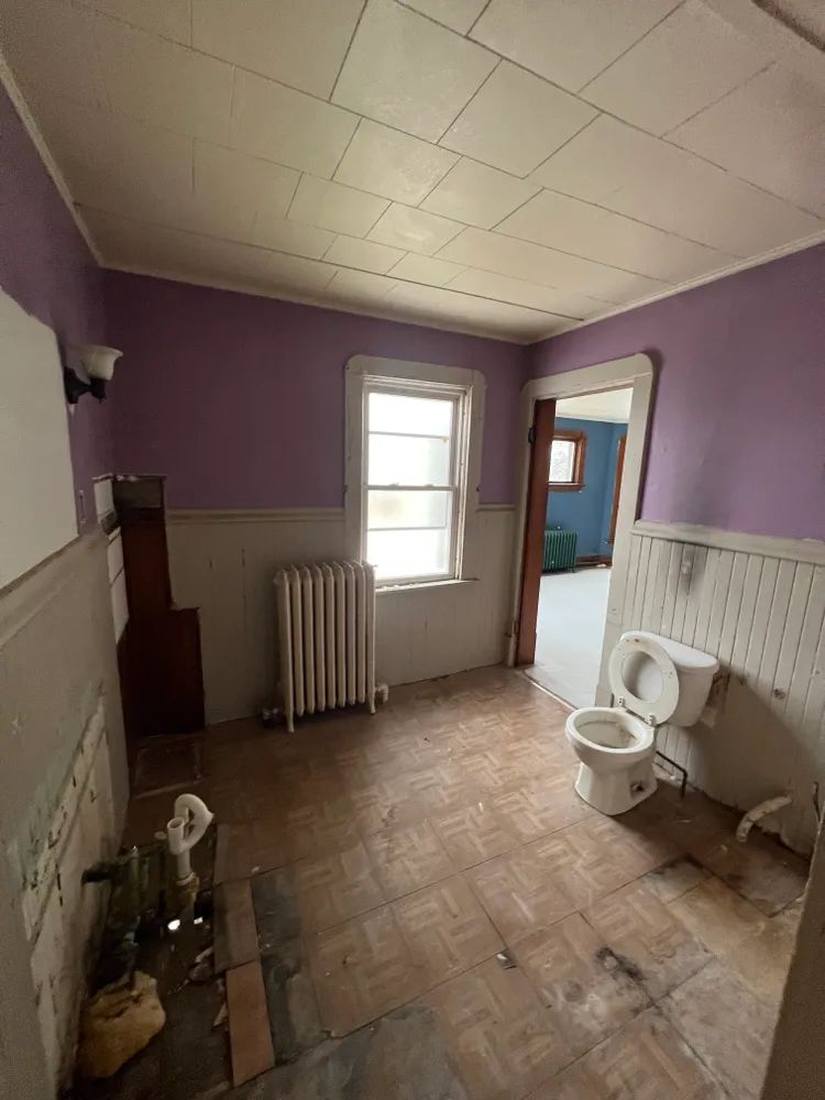 An empty bathroom with purple walls and a toilet.