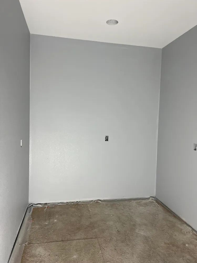 An empty room with gray walls and a concrete floor.