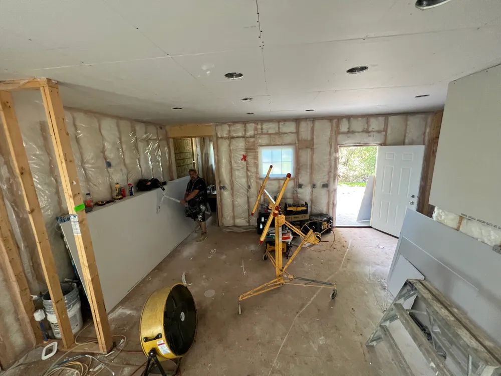 A man is sitting on a chair in a room that is being remodeled.