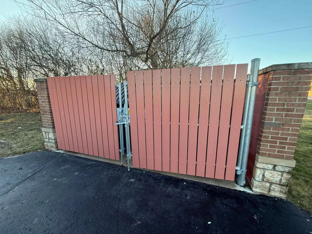 A red wooden fence is sitting next to a brick wall.