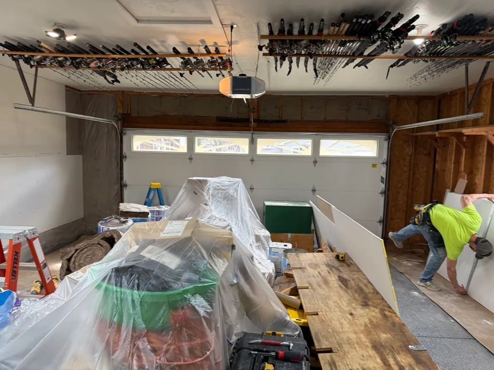 A man is working on a wall in a garage.