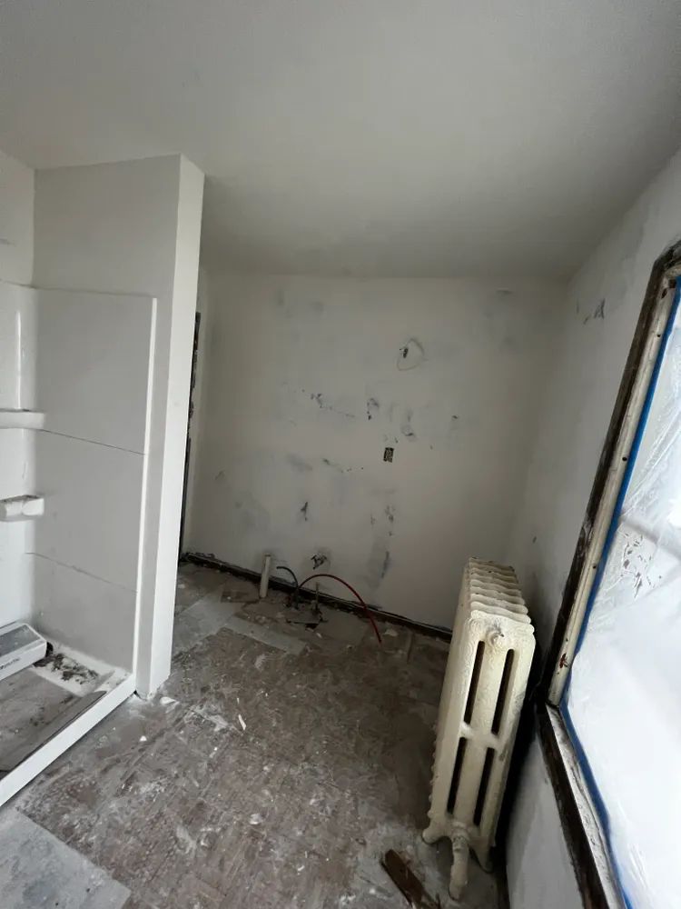 An empty room with a radiator and a window