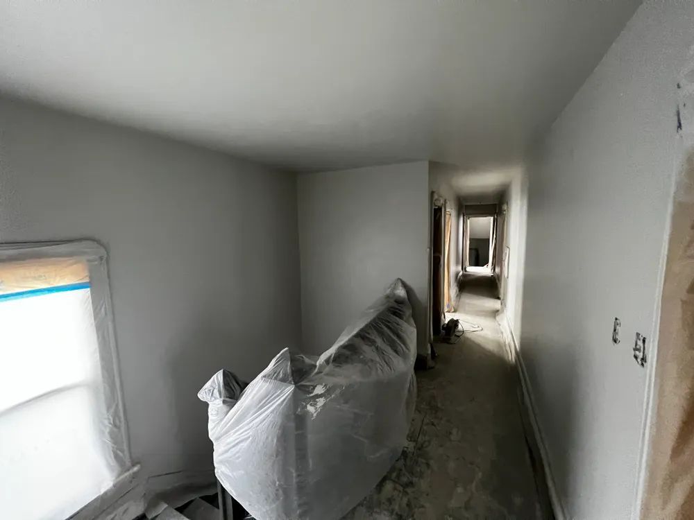 A room with white walls and a couch wrapped in plastic.