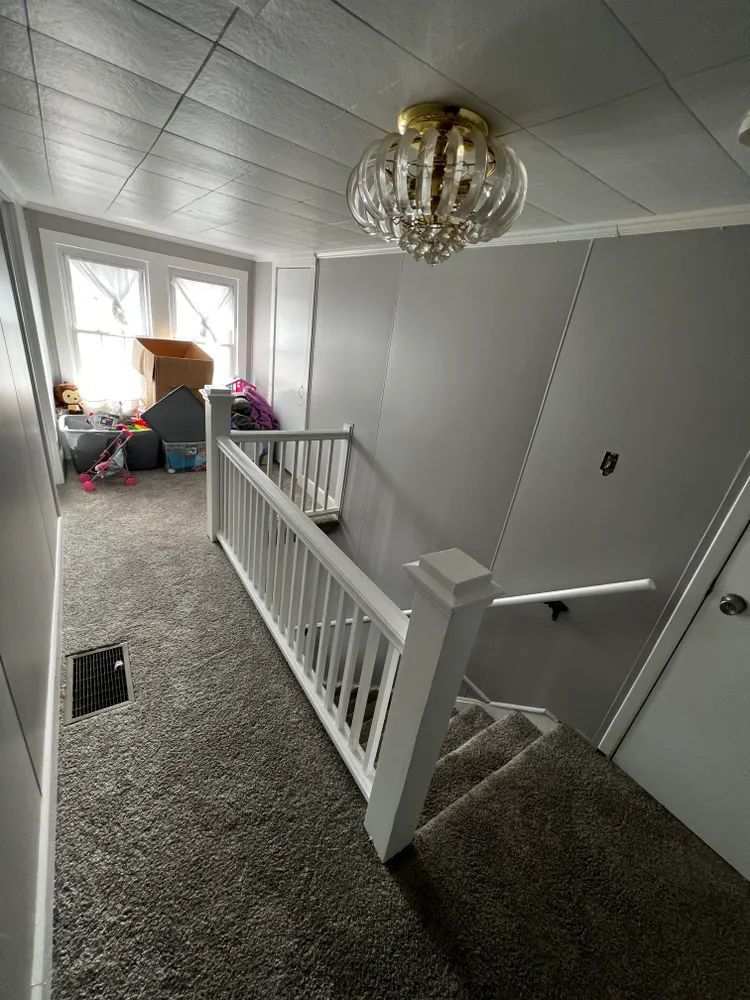 A hallway with stairs and a chandelier hanging from the ceiling.