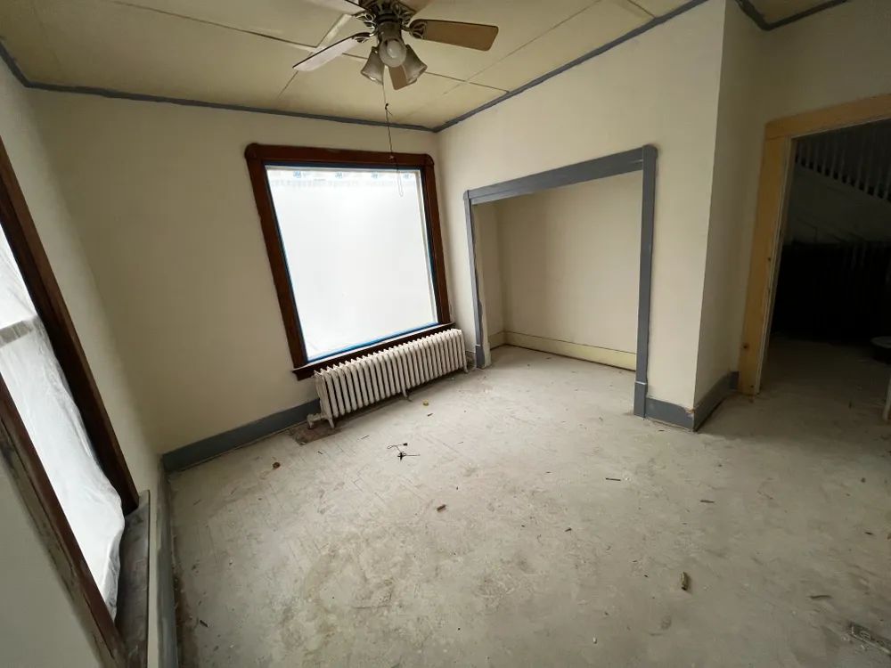 An empty room with a ceiling fan and a window.