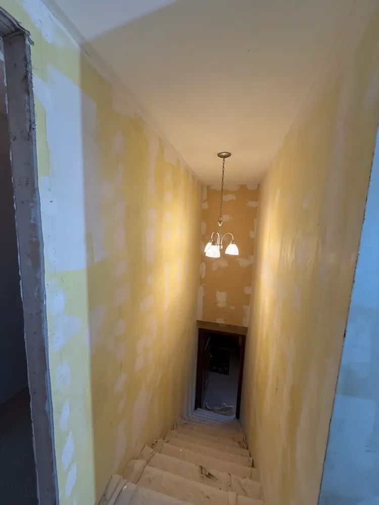 A hallway with stairs and a light hanging from the ceiling.