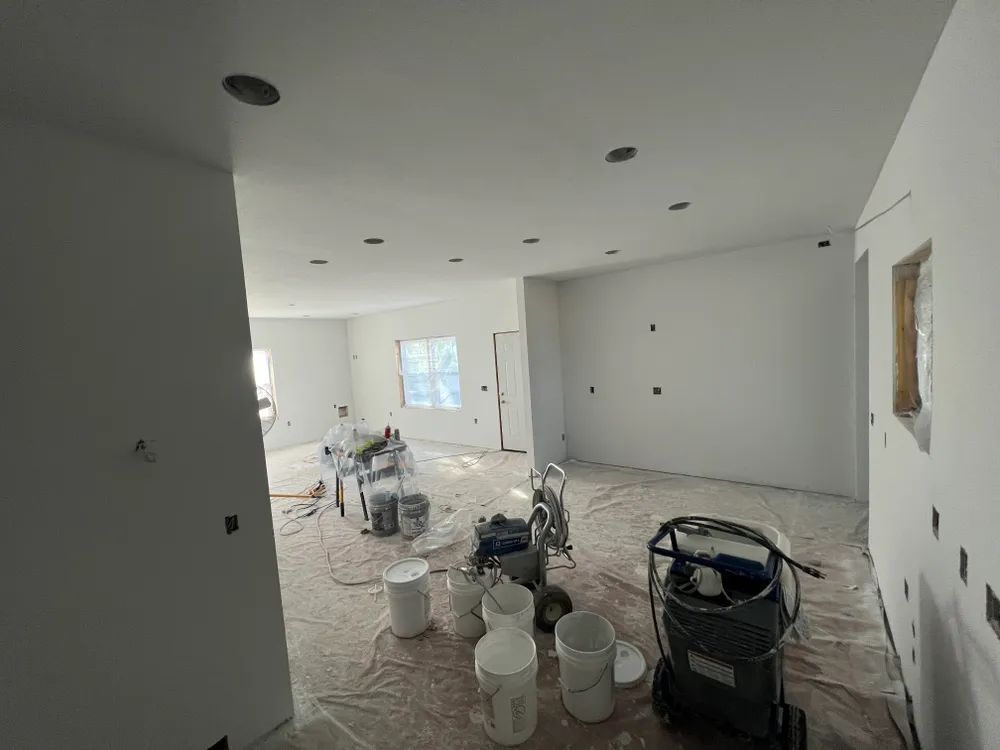 A room that is being painted with buckets and a vacuum cleaner.