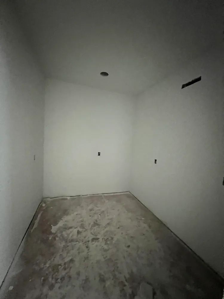 An empty room with white walls and a concrete floor.