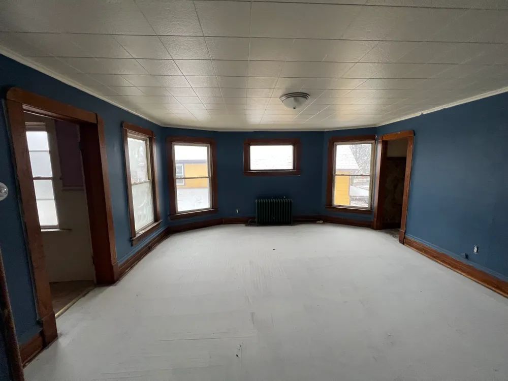 A large empty room with blue walls and white carpet.