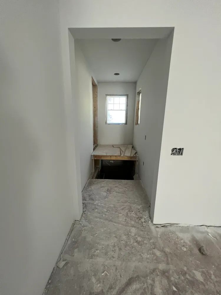 A hallway in a house under construction with a window.