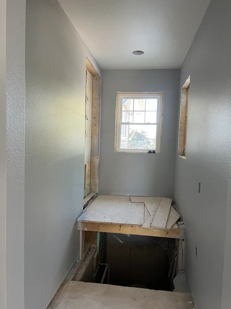 A hallway with a window and a wooden floor in a house under construction.