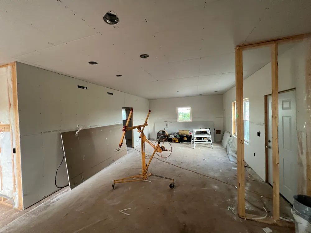 A room that is being remodeled with drywall and a crane.