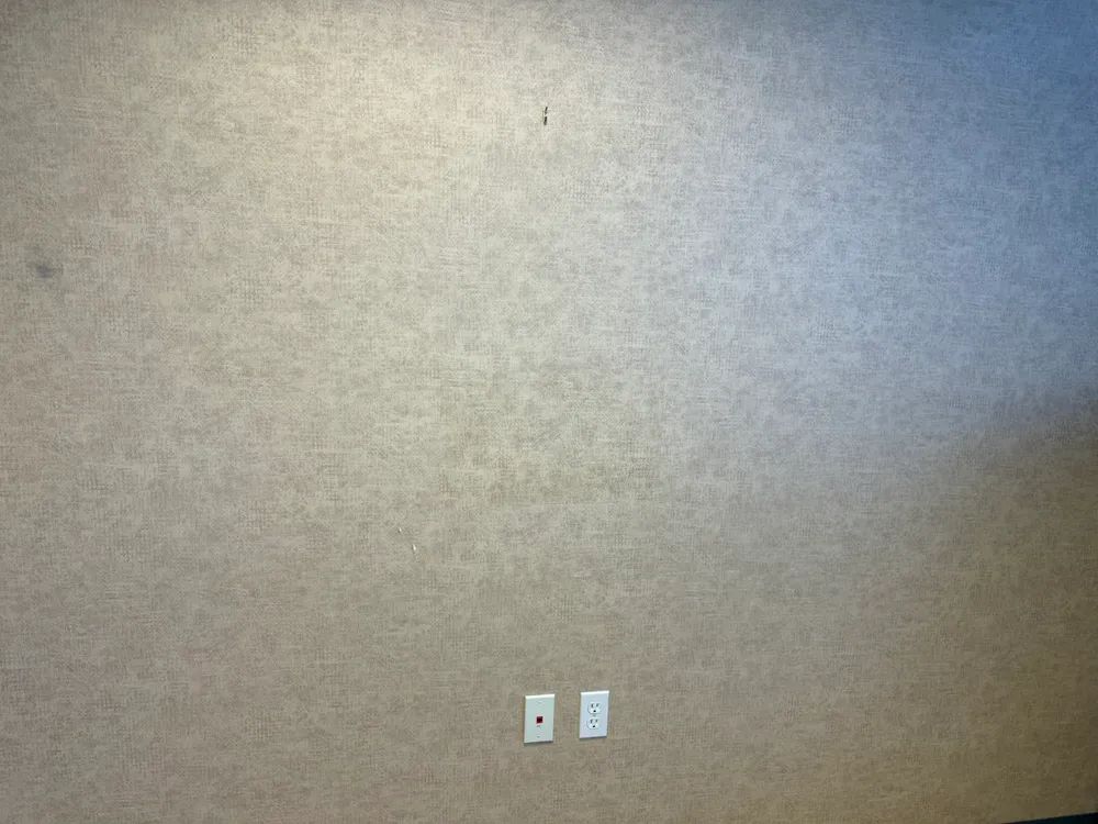 A gray wall with two white electrical outlets on it.