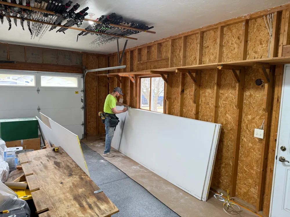 A man is working on a wall in a garage.