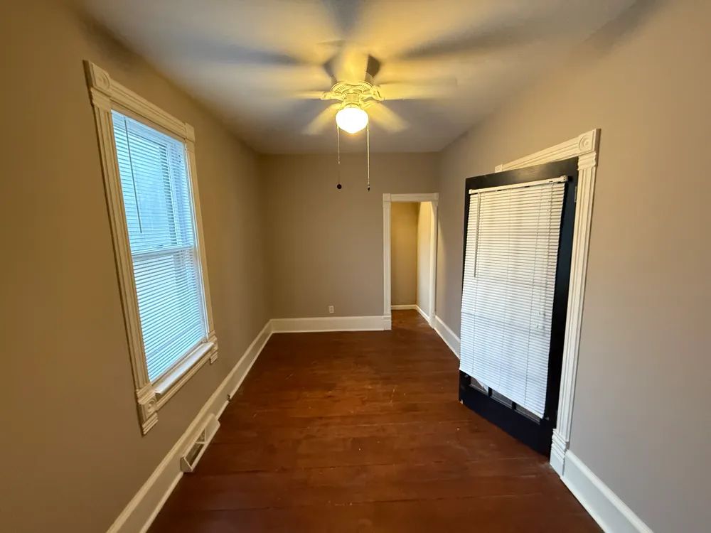 An empty room with a ceiling fan and a window.