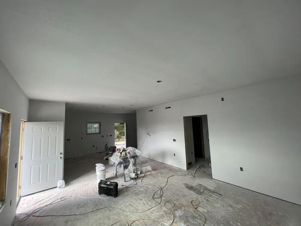 A large room with white walls and a white door is being painted.