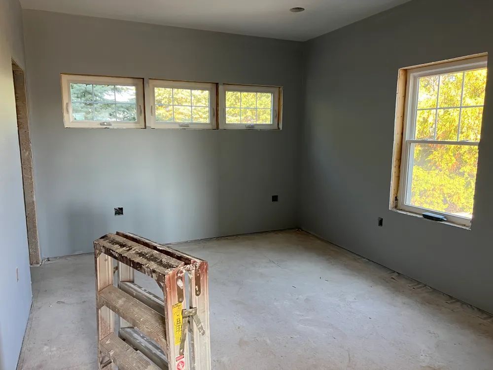 An empty room with a wooden ladder in the middle of it.