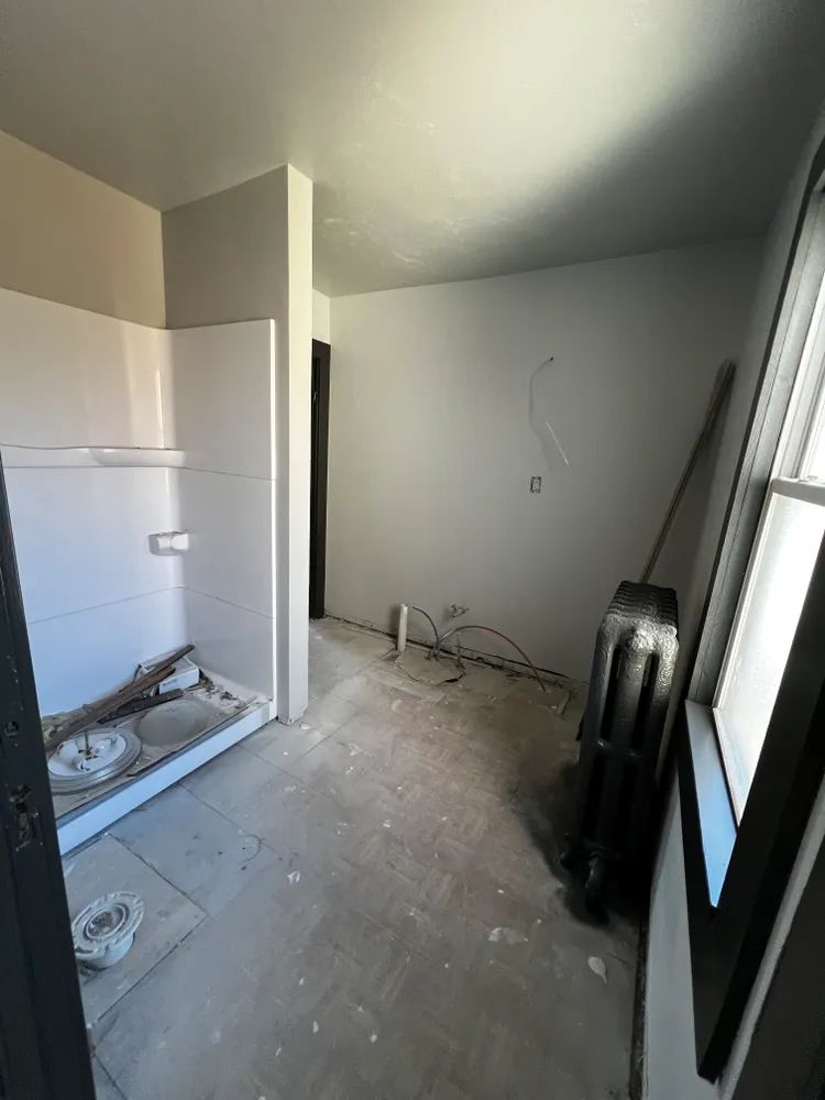 An empty bathroom with a shower stall and a window.
