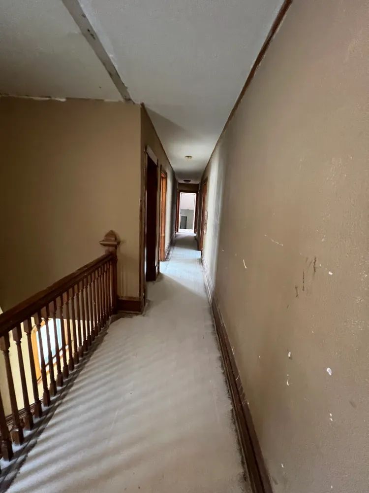 A long hallway with a wooden railing leading to a staircase.