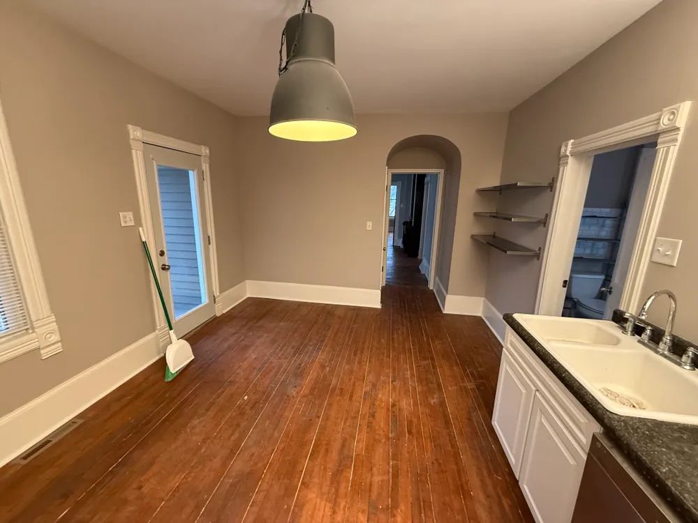An empty kitchen with hardwood floors and a sink.