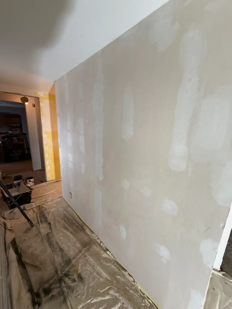 A large white wall is being plastered in a room.