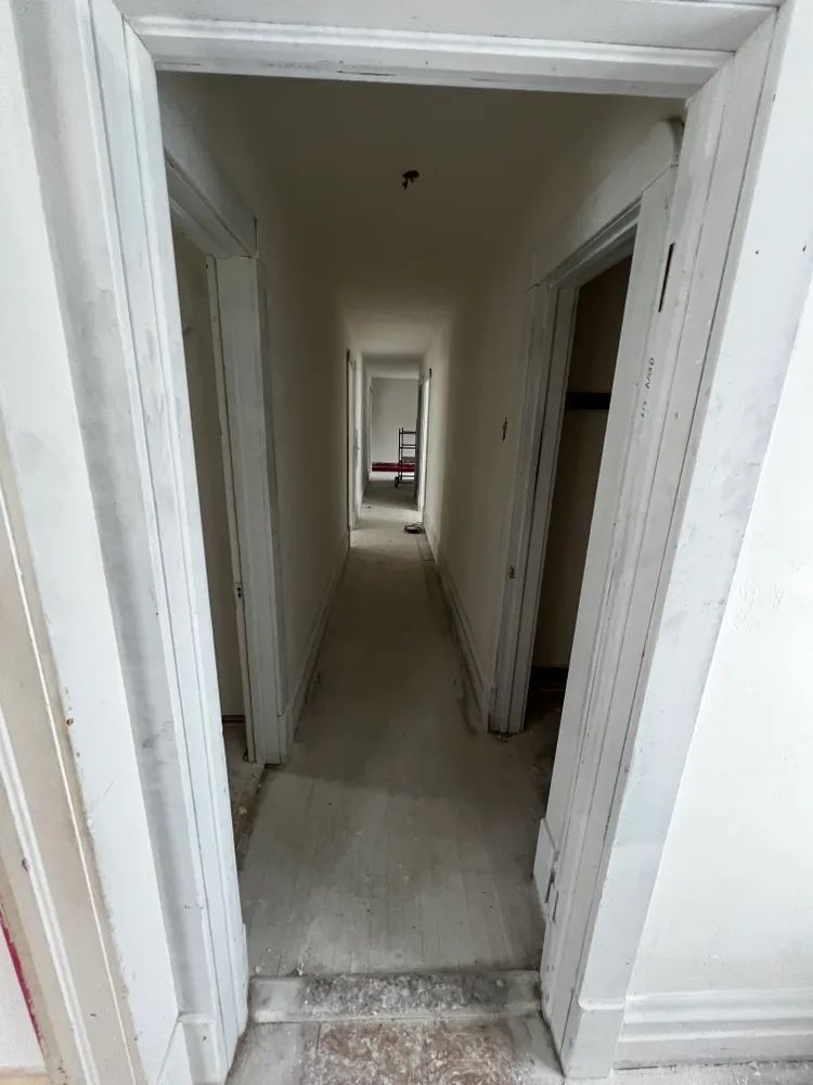 An empty hallway with a door open and a chair in the corner.