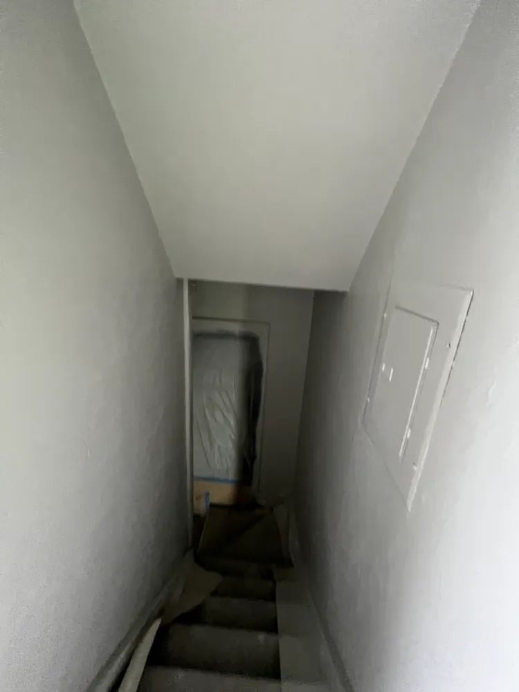 A narrow hallway with stairs leading up to a room.