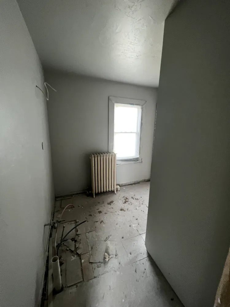 An empty room with a radiator and a window.