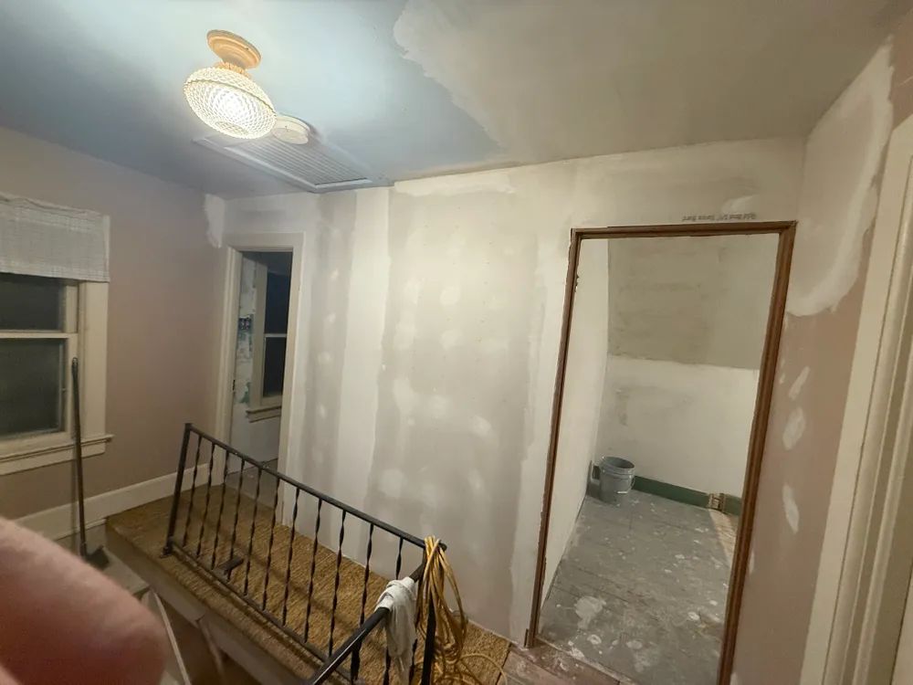 A room with a staircase and a door that is being painted.