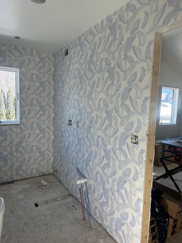A room with a wall that is covered in wallpaper and a window.