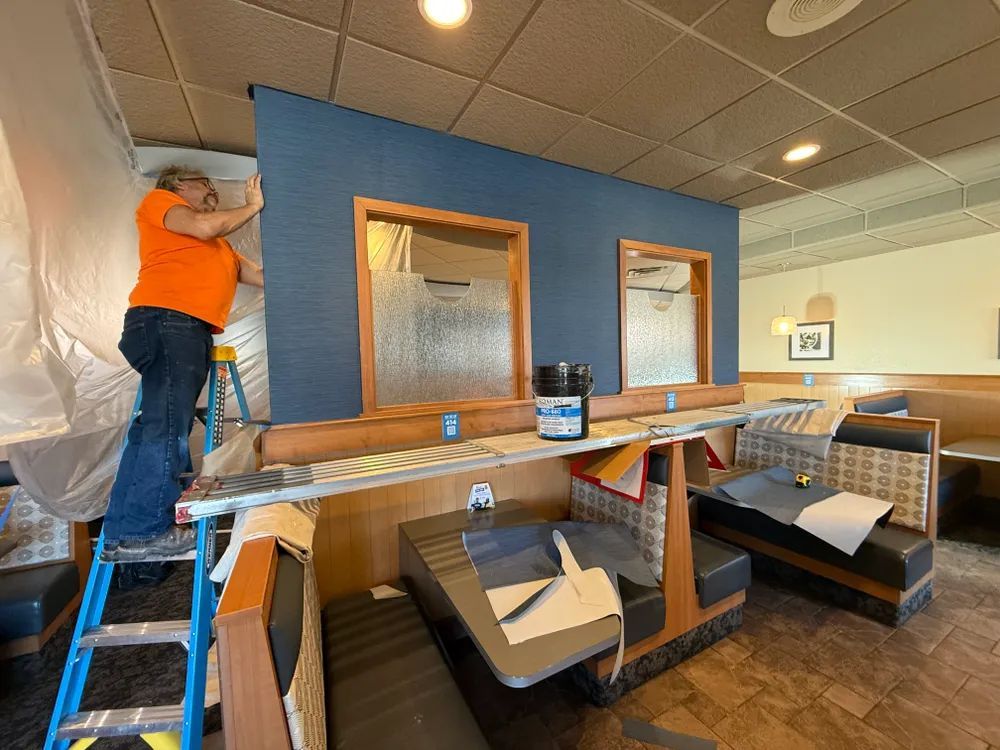 A woman is standing on a ladder in a restaurant.