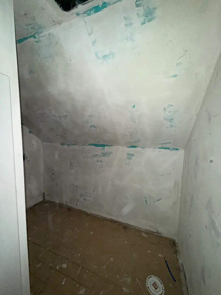 An empty room with a slanted ceiling and white walls.