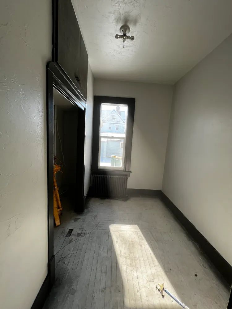 An empty room with a window and a ceiling fan.