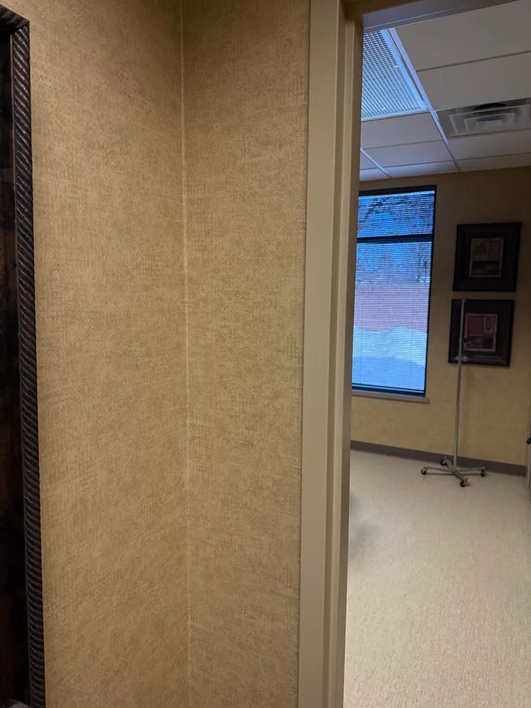 A hallway with a doorway leading to a room with a window.