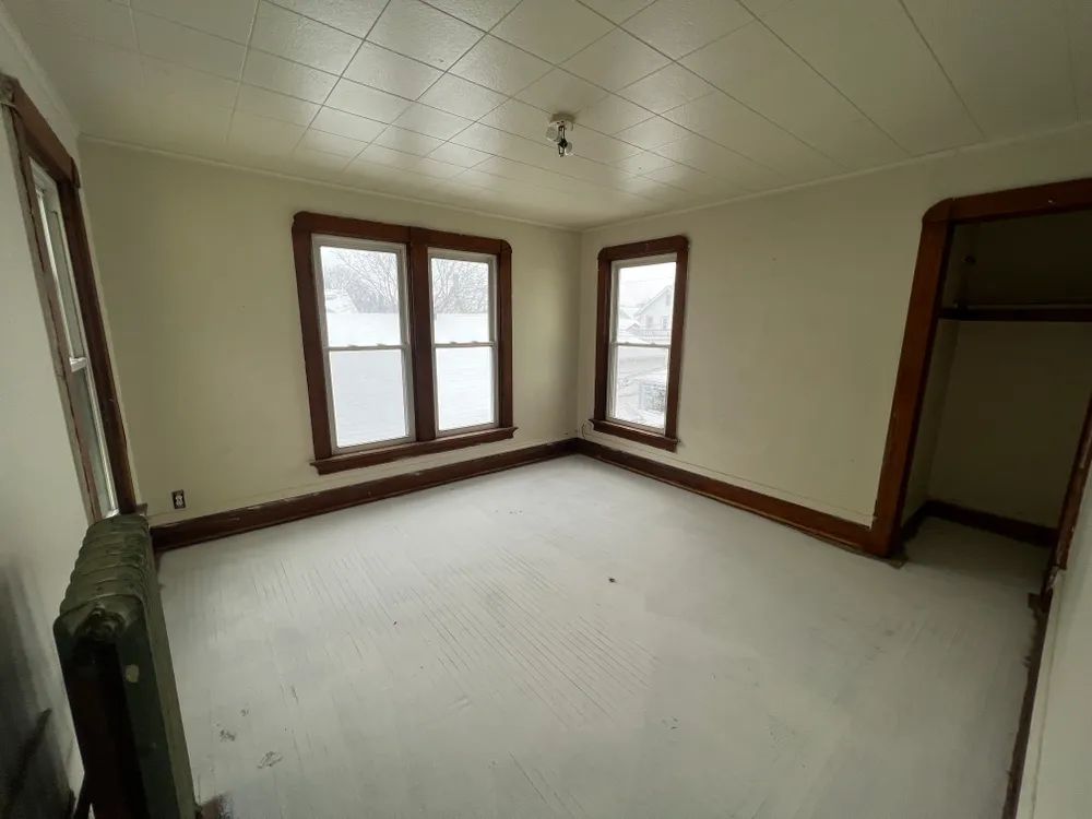 An empty room with three windows and a radiator.