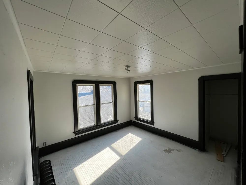 An empty room with two windows and a white ceiling