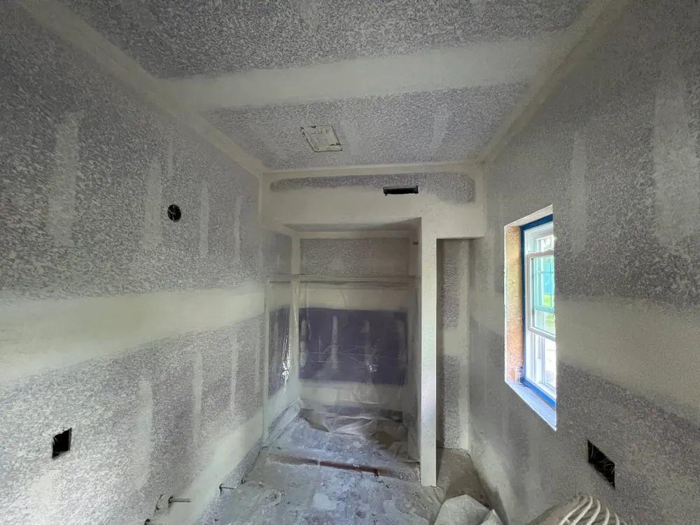 A room with drywall on the walls and a window.