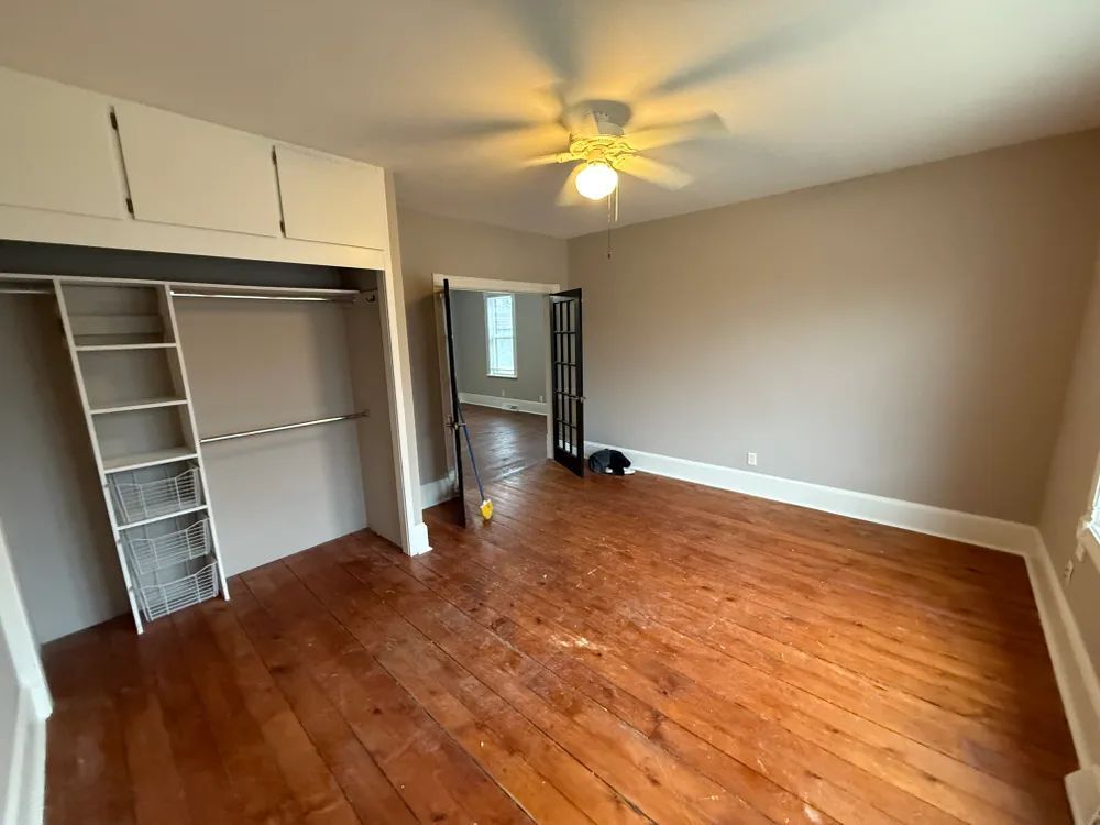 An empty room with hardwood floors and a ceiling fan.