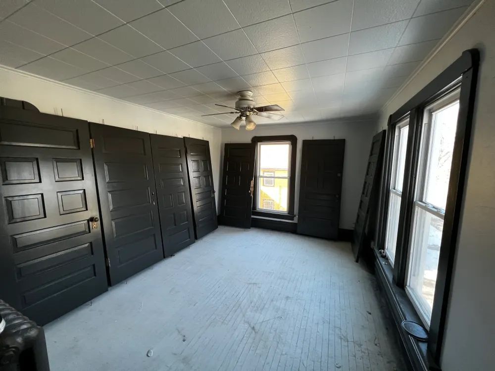 An empty room with black doors and windows and a ceiling fan.